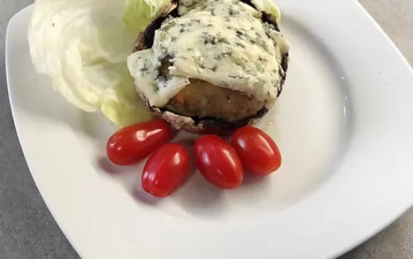 Nejdříve ulomte žampionům nožičky. Dejte na pánvičku rozehřát máslo, nakrájejte nožičky a cibulku. Orestujte to na rozehřátém másle. 
Do misky dejte kuřecí mleté maso, přidejte orestovanou cibulku a nožky ze žampionů., česnek, vejce a nastrouhaný sýr. Důkladně vše promícháme. Do pekáčku na pečící papír uděláme deset kusů karbanátků. Pečeme je při 150 stupních dvacet minut. 
Připravíme si další pekáček, kam připravíme  portobella. 
Upečené karbanátky položíme na portobella. Vršek pokryjeme tenoučkými plátky nivy. Dáme zapéct na deset minut na 150 stupňů. Zapečené portobello jsem servírovala se salátem z ledového salátu, chcerry rajčat a okurky. Salát  dochutila jsem balsamikovým