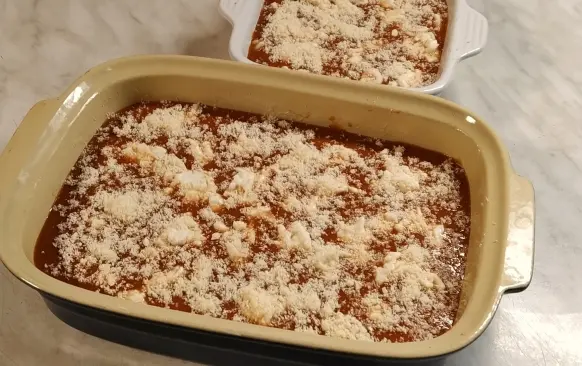 Trubičky zalijeme rajčatovou omáčkou (část omáčky si můžeme nechat na servírování), poklademe nastrouhanou mozzarellou a posypeme nastrouhaným sýrem parmezánového typu.