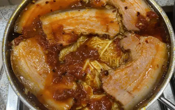 Na konec na vrch položíme několik plátků bůčku nebo slaniny, zalijeme  vývarem z kapusty a necháme dusit. V průběhu dušení přidáme směs rajčatového protlaku, čili, a dalšího koření podle chuti.
Dusíme asi 1,5 hodiny.